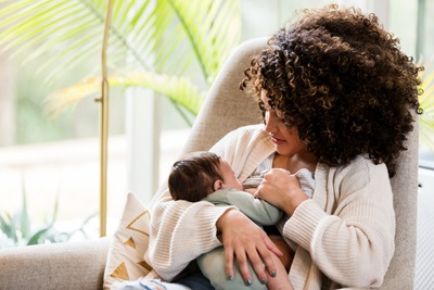 mom breastfeeding newborn in chair