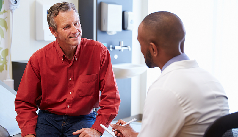 male doctor talking to male patient in hospital room